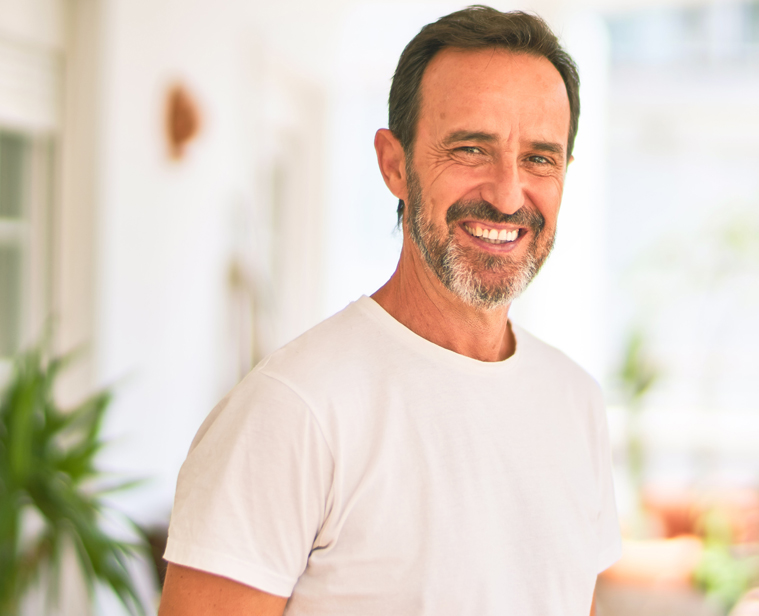 Middle age handsome man wearing casual t-shirt standing on terrace smiling